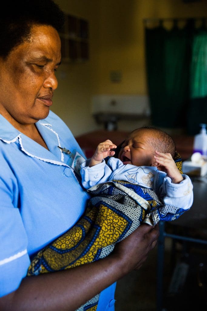 A nurse holds a newborn crying baby