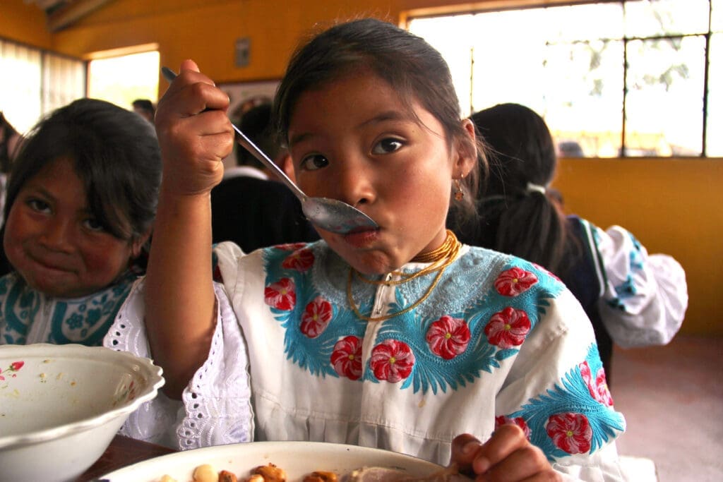a young girl eats a meal at school