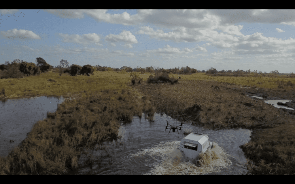 Drone footage of a SHERP vehicle driving through a river