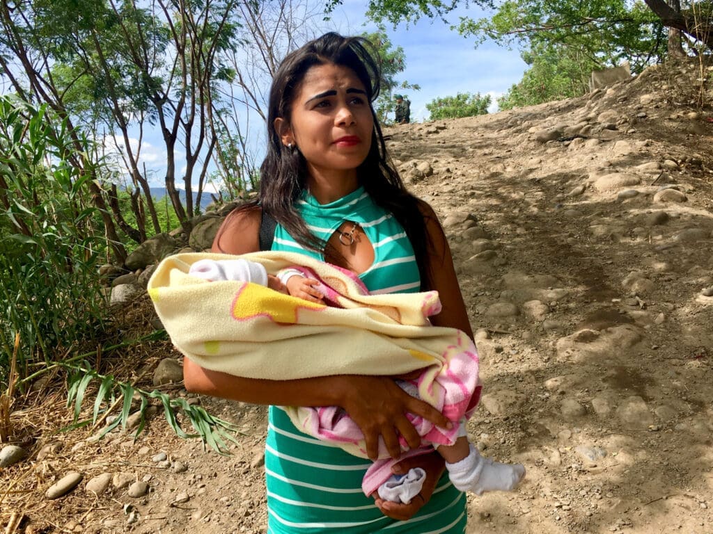 A mother carries her baby from Venezuela to Colombia to get medicine