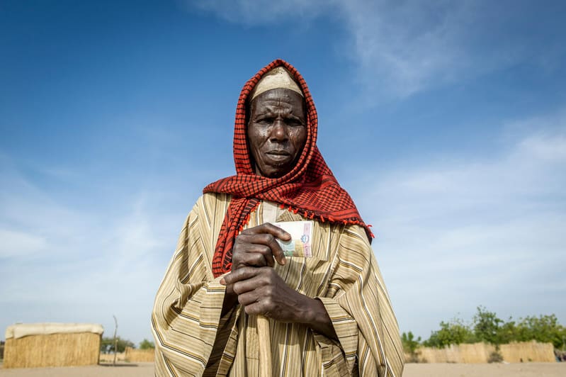 a woman in red headscarf holds cash from WFP