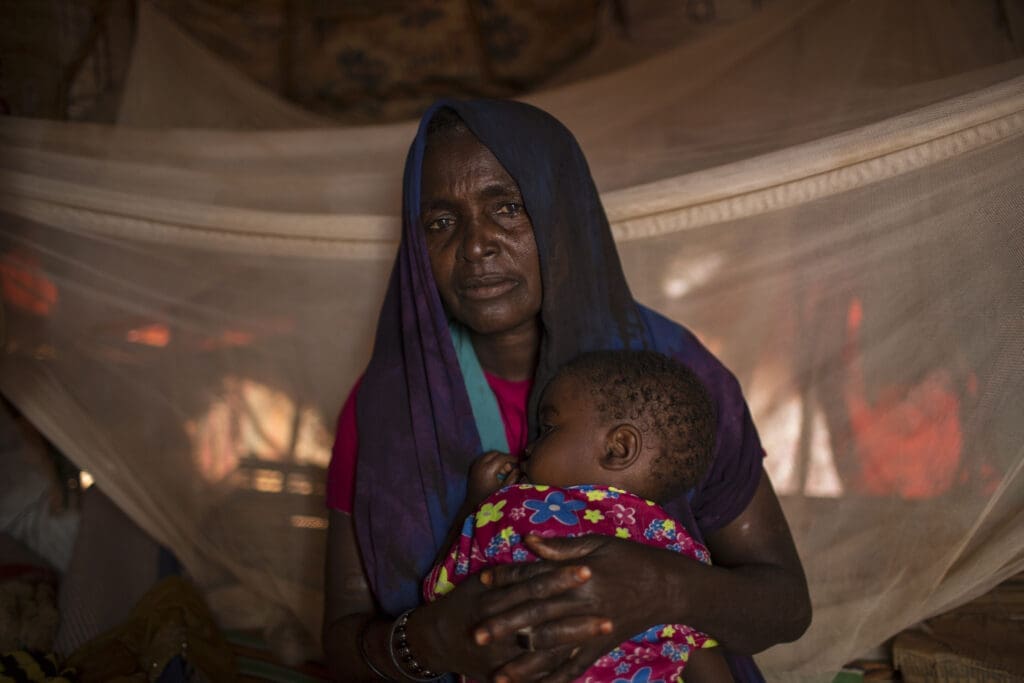 A woman comforts her granddaughter at her home in a camp for IDPs