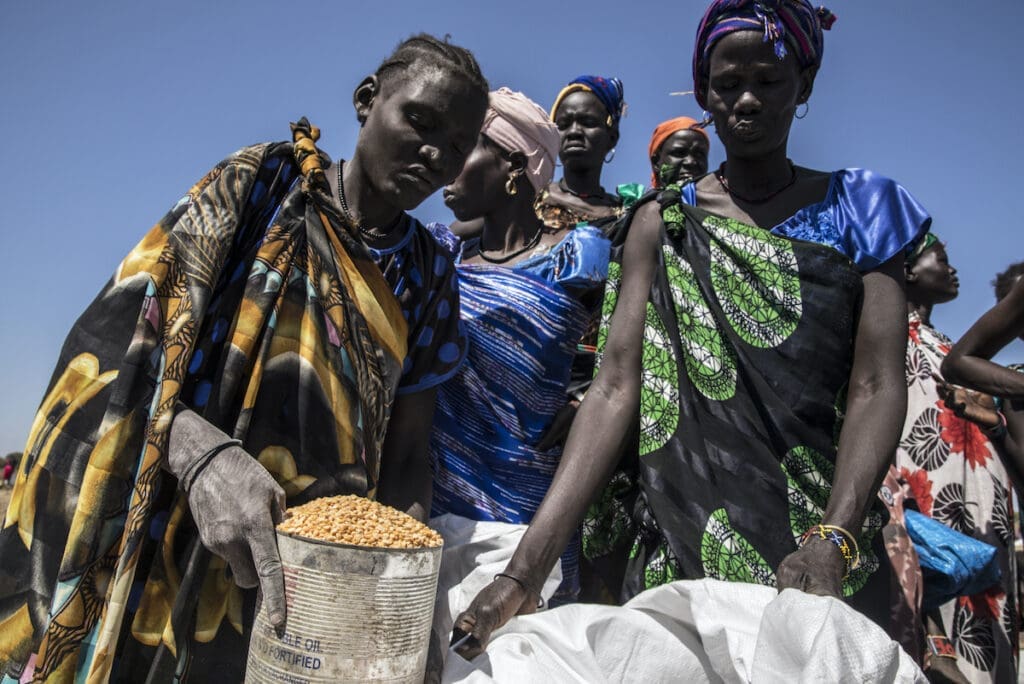 A group of women lean over bags of food.