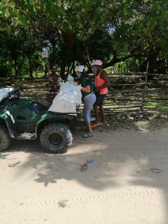 Two teachers unload food from an ATV