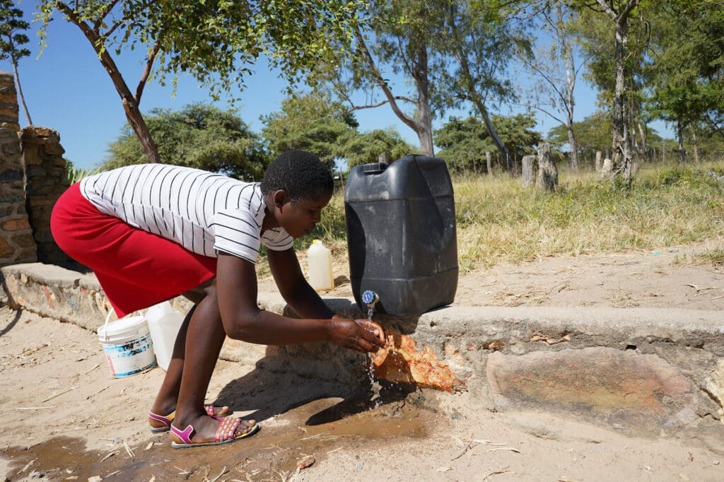 A woman washes her hands at a at a hand washing station.