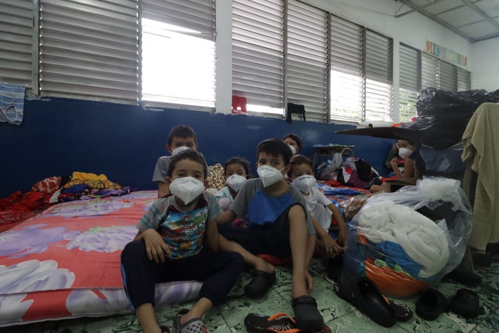 masked children sitting on mattresses on the floor