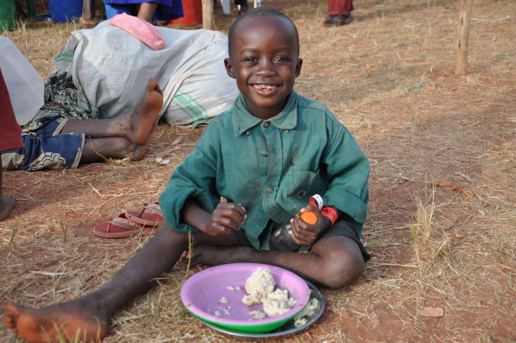 a young boy eats porridge while smiling