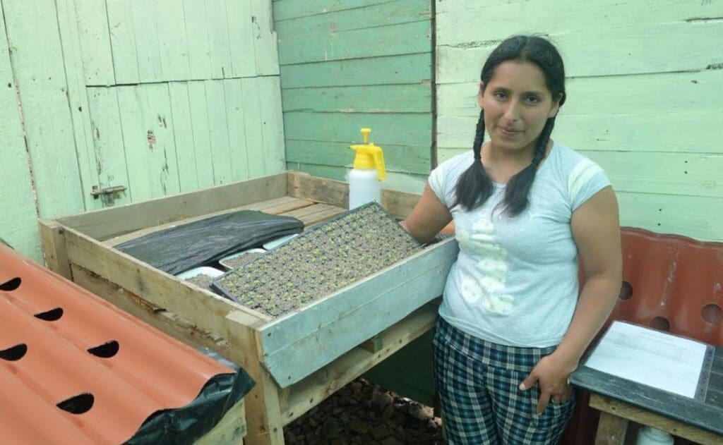 A young woman stands next to hydroponic supplies.