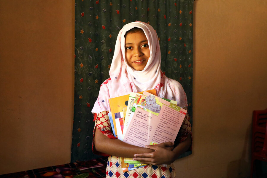 young schoolgirl in pink headscarf holding book