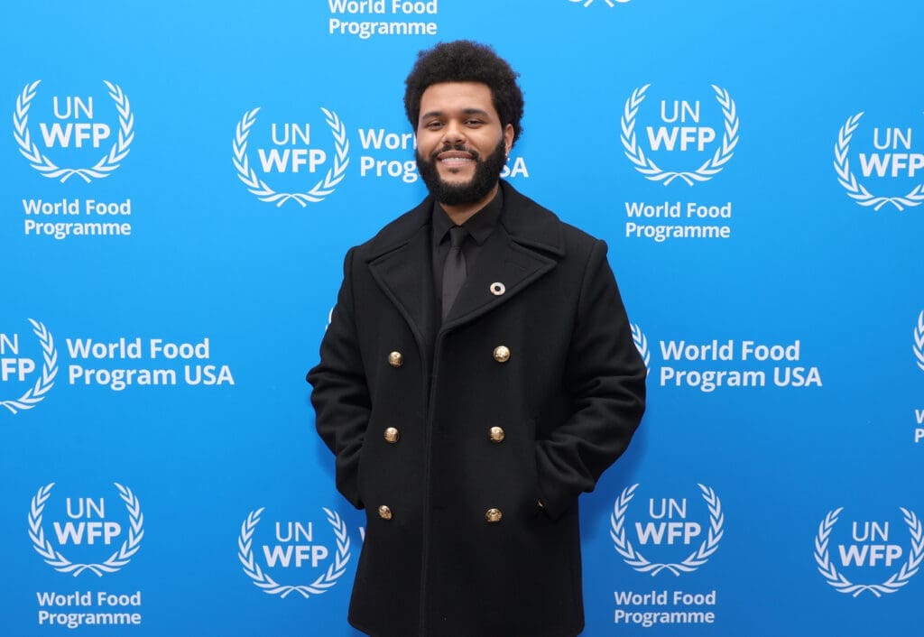 The Weeknd stands in front of WFP USA banner