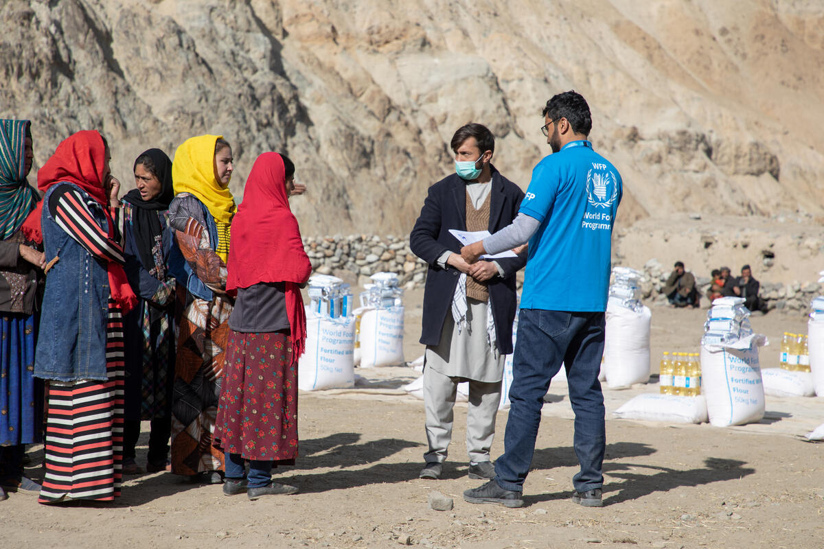 WFP staff distributing food outside to women