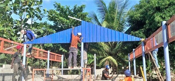 construction workers rebuilding school with blue roof