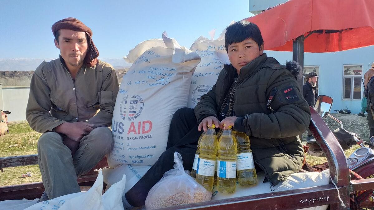 men sitting in truck with bags of food and vegetable oil