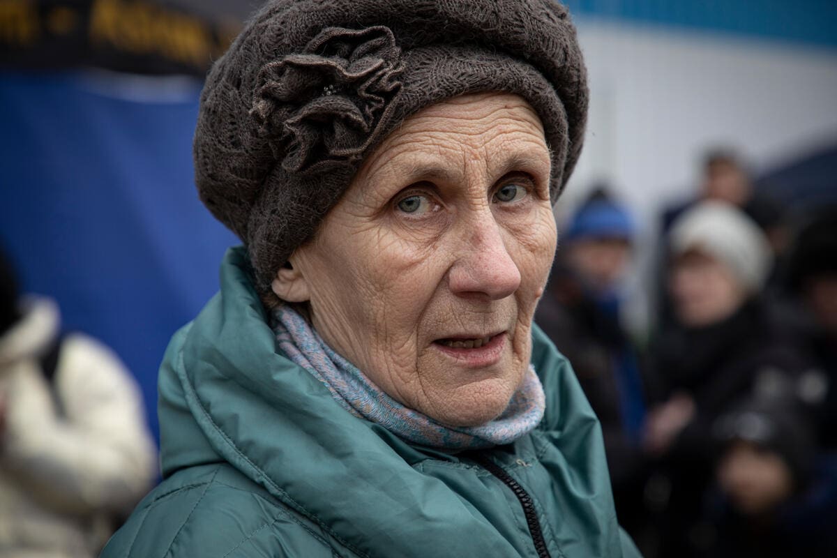older woman in brown hat and green winter coat