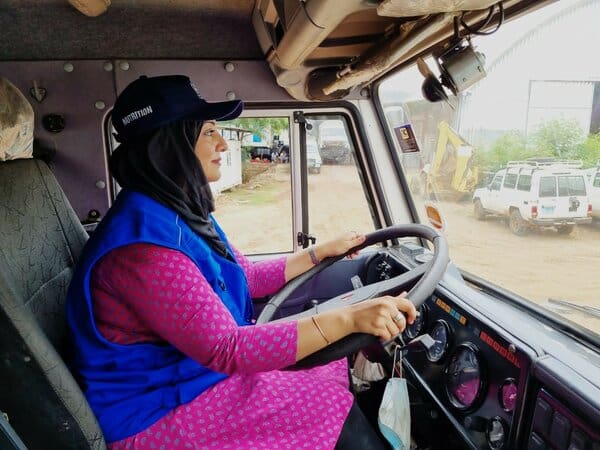 woman in blue vest driving truck