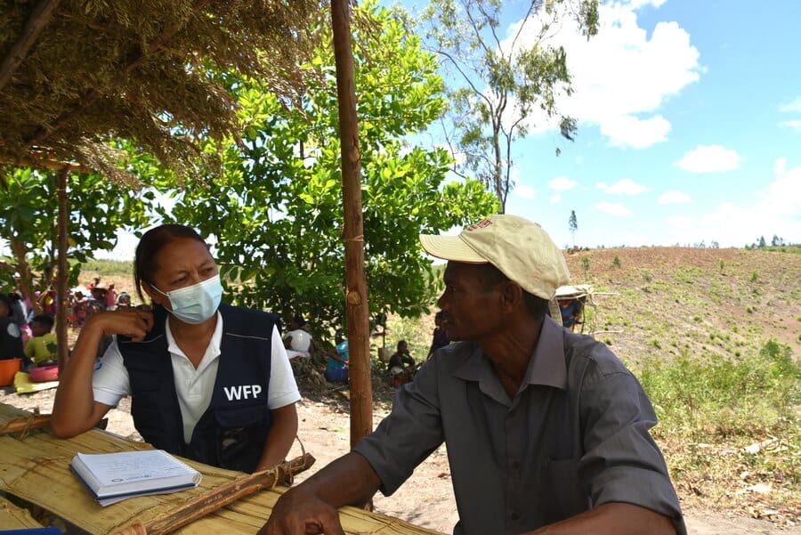 woman in WFP vest and COVID mask speaking with man
