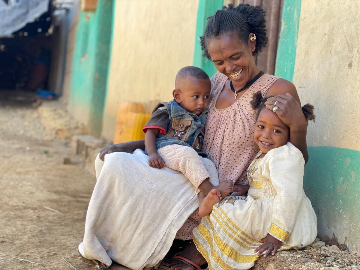 mother smiling and holding two children