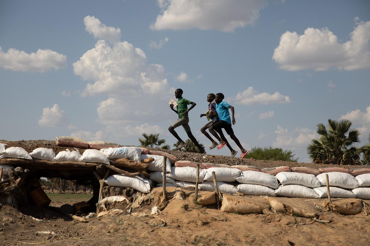 Children run over dike in South Sudan